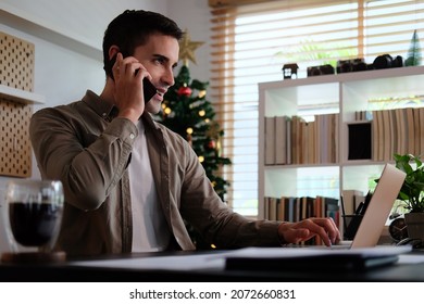 Young man working with computer laptop and talking on mobile phone.