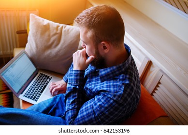 Young man working with computer on the beach. Handsome man working with laptop laying on the couch at the beach.