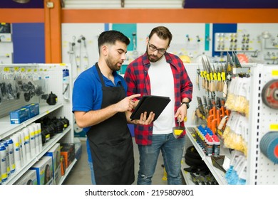 Young man working in customer assistance at the hardware store and talking with a client shopping at the hardware store