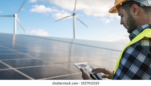 Young man working with digital tablet at renewable energy farm - Eco and technology concept - Focus on ear