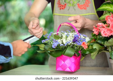 Young Man Working As Florist Giving Credit Card To Customer After Purchase.