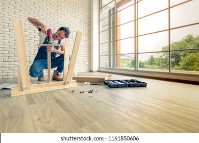 Young man working as handyman, assembling wood table with equipments, concept for home diy and self service.in the office there is a white brick block.