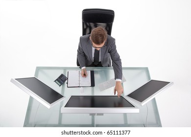 Young Man Working At His Desk Showing With The Finger On His Monitor