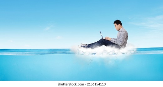 Young Man Working With A Laptop On The Cloud While Floating On The Sea With Blue Sky Background