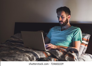 Young Man Working Late In Bed On A Laptop