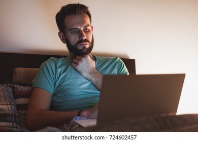 Young man working late in bed on a laptop - Powered by Shutterstock