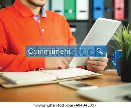 Young man working in an office with tablet pc and searching COMMITMENT word on internet