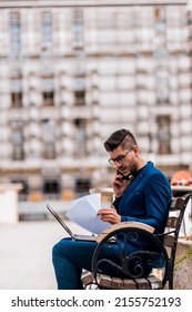 Young man working on bench at urban place while using laptop