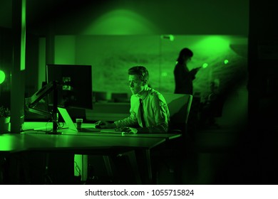 Young man working on computer at night in dark office. The designer works in the later time.