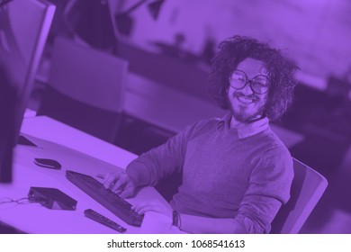 Young man working on computer at night in dark startup office. The designer works in the later time. duo tone