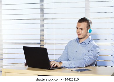 Young man working on computer and listening to music