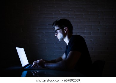 Young Man Working On Computer At Night In Dark Office. The Designer Works In The Later Time. 