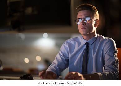 Young Man Working On Computer At Night In Dark Office. The Designer Works In The Later Time.