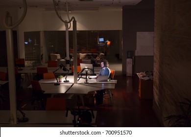 Young Man Working On Computer At Night In Dark Office. The Designer Works In The Later Time.