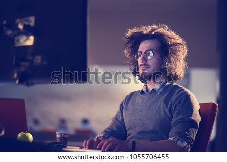 Young man working on computer at night in dark office. The designer works in the later time.