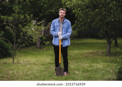 young man working on the farm, portrait of farmer holding a shovel - Powered by Shutterstock