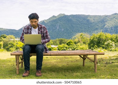 Young Man Working On His Laptop Connect To Wireless Internet In Rural Area. Internet Connection Allows People To Work Anywhere.