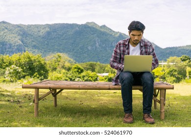 Young Man Working On His Laptop Connect To Wireless Internet In Rural Area. Internet Connection Allows People To Work Anywhere.