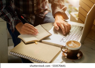 Young Man Working On His Laptop In A Coffee Shop In Morning.