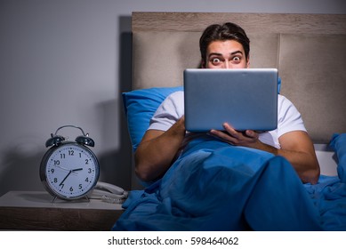 Young Man Working On Laptop In Bed