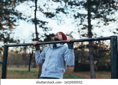 Young Man Working Out In Outdoor Gym In Park