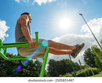 Young man working out in outdoor gym, doing leg lifting abs exercise . Staying fit and healthy. - Powered by Shutterstock