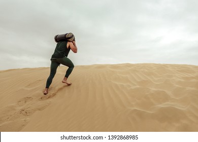 Young Man Working Out With A Sandbag In The Desert