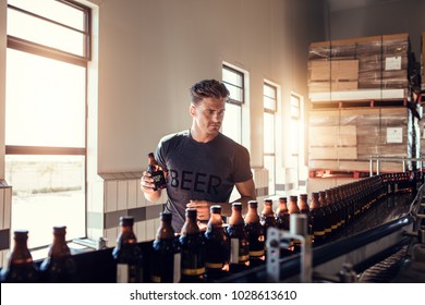 Young man working at small craft beer making factory and checking the quality of beer. Young businessman testing the beer bottle at brewery. - Powered by Shutterstock