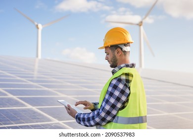Young man working at solar power station using digital tablet - Renewable energry with wind turbines and solar panels