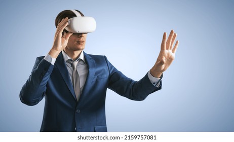 Young Man Working In Virtual Reality Office In VR Glasses, Presses His Hand Virtual Interface On Abstract Light Blue Backdrop. Innovate And Future Technology Concept, Close Up