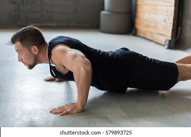 Young man workout in fitness club. Profile portrait of caucasian guy making plank or push ups exercise, training indoors - Shutterstock ID 579893725