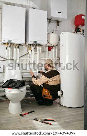 Young man in workwear using handtools during repairing work in toilet