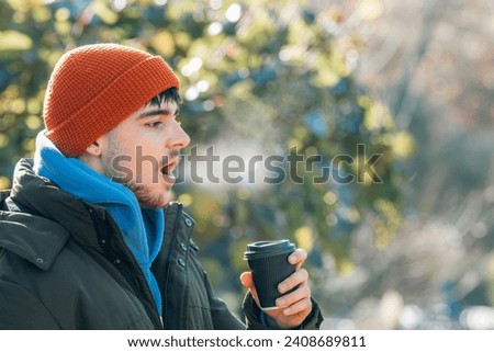 young man wrapped up in winter breathing halo of cold