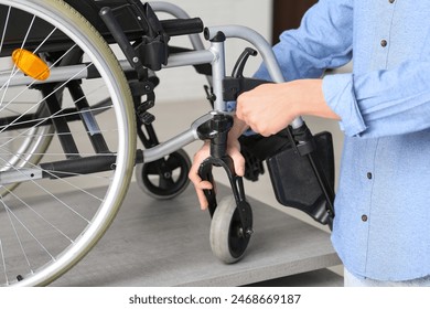 Young man with wrench repairing wheelchair on table at home, closeup - Powered by Shutterstock