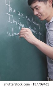 Young Man Writing English Sentences On The Blackboard