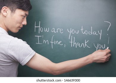 Young Man Writing English Sentences On The Blackboard