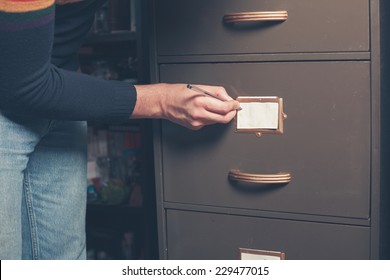 A Young Man Is Writing A Note On An Old File Cabinet