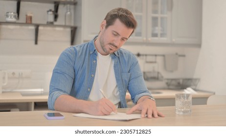 Young Man Writing while Doing Paperwork
