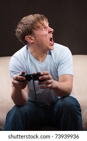 young man yelling at someone while playing video games on gray background