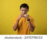 A young man in a yellow shirt adopts a fighting stance with fists raised near his face, looking focused. The background is yellow.