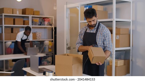 Young Manager In Post Room Packing Order For Distribution. Online Store Warehouse Manager Pack Parcel In Cardboard Box At Workshop