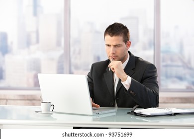 Young manager sitting at desk in bright office, working on laptop.? - Powered by Shutterstock