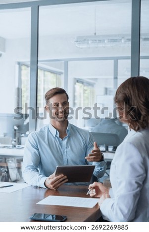 Young manager worker man talking with bank client in office. Business meeting entrepreneur people sitting at table, using gadget tablet device, discussing trade strategy or cv on interview. Vertical