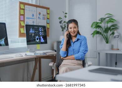 Young manager working with statistics data in modern office, analyzing diagrams while sitting at desk and discussing strategy with partners on mobile phone