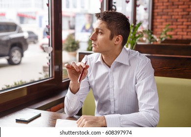 Young manager working writes in a notebook outdoors. Freelancer works in a cafe. - Shutterstock ID 608397974