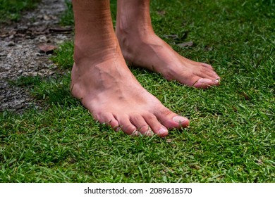 Young Man's Bare Feet On The Grass