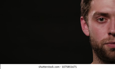 A young man's half face against a black background. Close-up shot