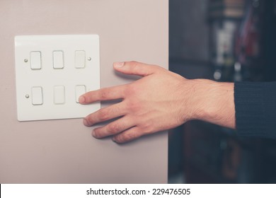 A Young Man's Hand Is Switching On A Light Switch At Home