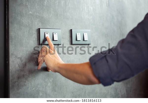 The young man\'s hand turned off the light\
switch\Energy saving\
concept