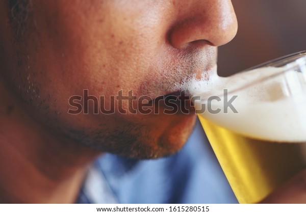 The young man\'s lips\
tasting the beer\'s flavors and feeling the softness of the beer\
bubbles.